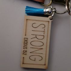 a wooden keychain with a blue tassel hanging from it