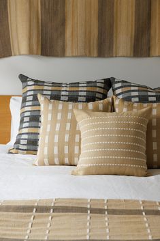 a bed with pillows and blankets on top of it in front of a wooden headboard