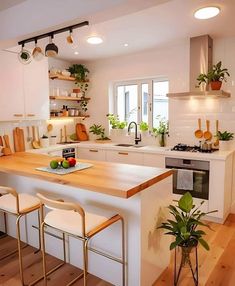 a kitchen with white cabinets and wooden counter tops, two stools at the island