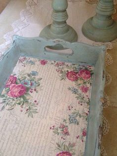 a blue tray with pink flowers on it and two candles in the background, sitting on a table