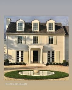 a large white house with lots of windows and a fountain in front of the door