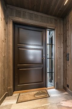 an entryway with a wooden door and glass paneled walls, along with a welcome mat on the floor