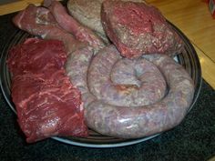 meats and sausages are on a plate ready to be cooked in the oven