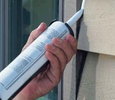 a person is holding an item in their hand near a window sill that has been taped to the side of a building