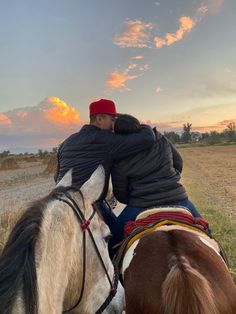 two people riding on the back of a brown and white horse next to a field