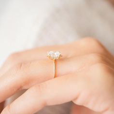 a woman's hand holding an engagement ring with a diamond in the middle, on top of her finger