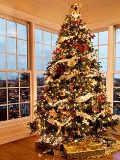 a decorated christmas tree in a living room with large windows and wooden flooring on the side