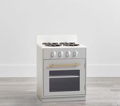 a white stove top oven sitting on top of a hard wood floor next to a wall