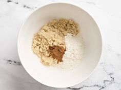 a white bowl filled with dry ingredients on top of a marble counter