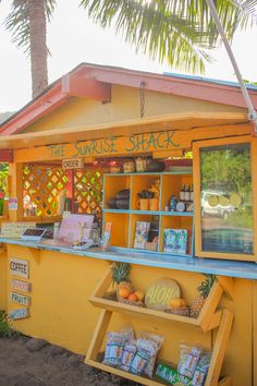 a small yellow stand with some food on it's display shelf and palm trees in the background