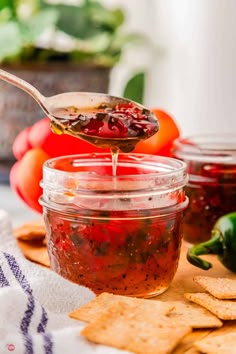 a spoon full of salsa being poured into a jar with tortilla chips on the side