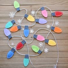 an assortment of felt christmas lights on a wooden table with snowflakes in the background