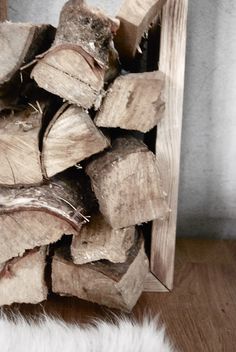 a pile of wood sitting on top of a wooden floor next to a white rug