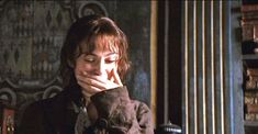 a woman sitting at a table with her hand on her face in front of bookshelves