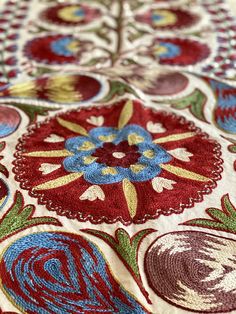 an intricately designed table cloth with red, blue and green designs on it's edges