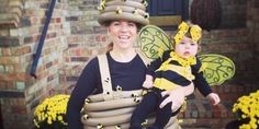 a woman holding a baby dressed as a bee