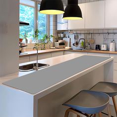 a kitchen with two lights hanging over the counter and stools in front of it