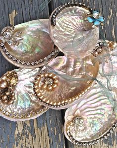 three seashells with pearls on them sitting on a wooden surface