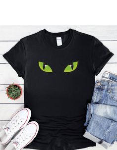 "Dive into the abyss of Halloween with our \"Monster Green Eyes\" T-shirt. This shirt features a pair of eerie green eyes that peer out from the darkness, capturing the mysterious allure of the season. Whether you're attending a Halloween party or just want to embrace the enigmatic, this shirt adds a touch of intrigue to your attire. Gaze into the unknown and let Halloween's mysteries unfold! This unisex soft-style t-shirt puts a new spin on casual comfort. Made from very soft material which is 100% cotton. The shoulders have twill tape for improved durability. There are no side seams. The collar is made with ribbed knitting to prevent curling damage.  .: 100% ring-spun cotton (fiber content may vary for different colors) .: Light fabric (4.5 oz/yd² (153 g/m .: Eurofit .: Tear-away label . Green Halloween T-shirt For Streetwear, Green Halloween T-shirt With Character Print, Eyes Halloween, Halloween Mystery, Into The Abyss, Halloween Graphic, Into The Unknown, Family Halloween, Simple Shirts