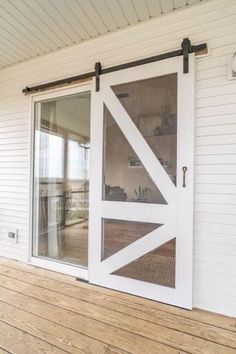 an open sliding door on the side of a white house with wood flooring and windows