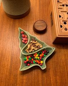 a wooden box with some candy in it on a table next to a christmas tree ornament