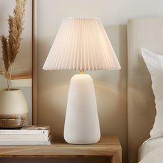 a white lamp sitting on top of a table next to a bed