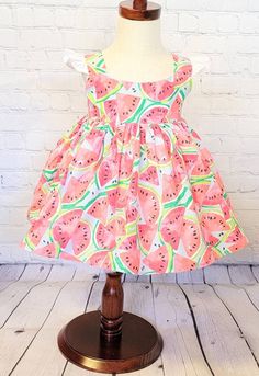 "Display dress is a size 18/24 month on a 2t mannequin. Dress is shown with a tulle petticoat underneath which is NOT INCLUDED in the purchase of dress. It is for display purposes only.  This watermelon dress features bright watermelons on a light blue background and has a full skirt, shoulder straps and ties at the waist. It would be so fun to wear to a picnic, a \"One in a Melon\" birthday or event.  Bodices are lined with soft white cotton and the back closes with Kam snaps for easy on and of Green Sleeveless Dress For Summer Dress-up, Cute Summer Dresses For Dress-up Occasions, Cute A-line Sundress For Garden Party, Sleeveless Fruit Print Dress For Vacation, Cute Green A-line Dress, Pink Fitted Bubble Dress For Summer, Pink Summer Twirl Dress With Ruffles, Pink Twirl Dress With Ruffles For Summer, Summer Beach Dress With Fruit Print