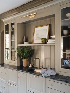 a kitchen with white cabinets and black counter tops, including a potted plant in the corner