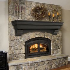 a stone fireplace with a wreath on top and candles in the corner next to it