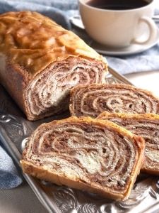 a loaf of cinnamon roll sitting on top of a metal tray next to a cup of coffee