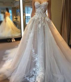 a woman in a wedding dress looking at herself in the mirror