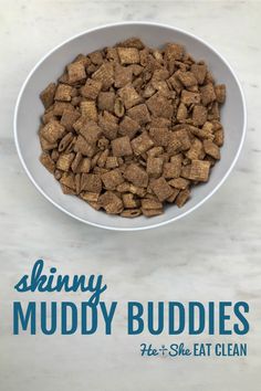 a white bowl filled with muddy buddies on top of a marble counter next to a blue and white sign that says skinnyy muddy buddies