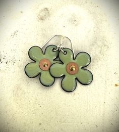 These sweet flower earrings will win you over with their cuteness! These earrings are made from copper flowers that are about 1 inch in diameter.  A center hole was drilled and they were gently shaped concave.  Multiple layers of a pretty lichen green enamel were added and fired in a kiln several times to create a soft, pretty green.  Edges have been left with a slight burnt edge for a more organic feel.  A tiny copper washer and rivet was added to the center. Finally, the earrings were finished with hand-forged ear wires made from sterling silver wire. This listing is for one pair of earrings only.  The 4th photo shows a similar pair of earrings with other earrings in my shop for both size and color comparison. Green Ombre, Daisy Earrings, Pretty Green, Oval Earring, Custom Earrings, Green Enamel, Square Earrings, Rivets, Silver Wire