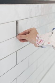 a person is holding onto a white brick wall