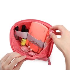 a hand holding a pink purse filled with cosmetics