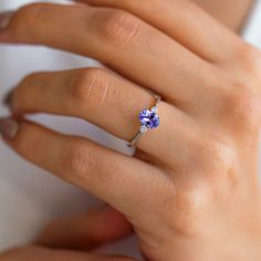 a woman's hand wearing a ring with a tan and purple flower on it