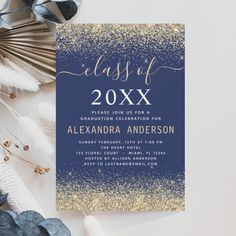 an elegant graduation party card with gold and blue glitters on it, next to some feathers