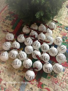 christmas ornaments with words on them sitting on a quilted tablecloth next to a tree