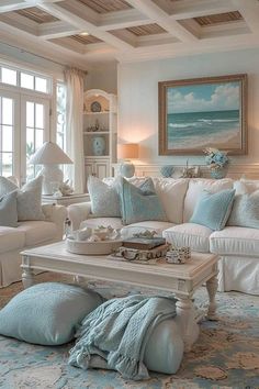 a living room filled with white furniture and blue pillows on top of it's couches