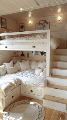 a bunk bed with white pillows on top and stairs leading up to the upper level