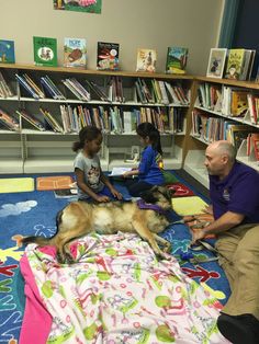 a man and two children sitting on the floor with a dog in front of them