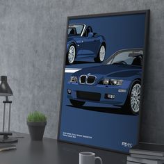 a blue bmw car poster on a desk next to a lamp and potted plant