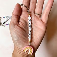 a person's hand holding a keychain with a rainbow charm on it