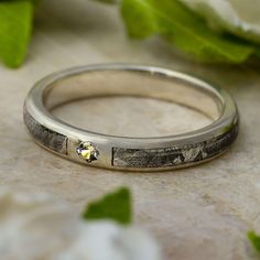 a close up of a wedding ring with flowers in the background