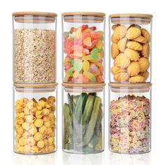 four glass containers filled with different types of candy beans and cereals on white background