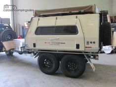 an off - road camper is parked in a garage next to other vehicles and boxes