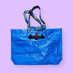 a blue tote bag on a purple background with a yellow and black strap around it