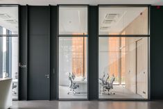 an empty office with glass walls and desks in the middle is seen from outside