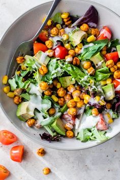 a salad in a bowl with dressing and tomatoes on the side, ready to be eaten