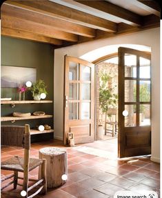 an open door leading into a living room with stone flooring and wooden furniture on either side